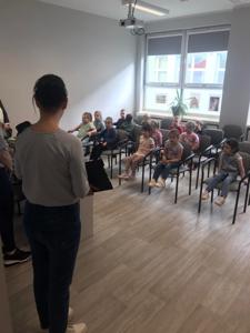 Na zdjęciu znajdują się uczestnicy zajęć. Dzieci siedzą na krzesłach. Zdjęcie wykonano w bibliotece.