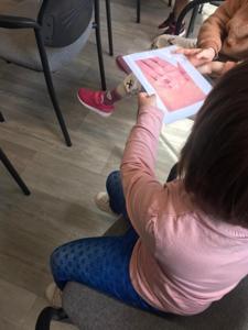 Na zdjęciu znajdują się uczestnicy zajęć. Dzieci siedzą na krzesłach. Zdjęcie wykonano w bibliotece.