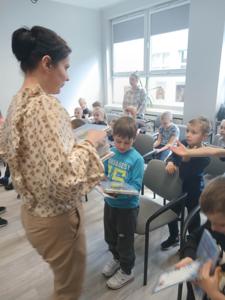 Na zdjęciu znajdują się uczestnicy pasowania. Dzieci siedzą na krzesłach. Zdjęcie wykonano w bibliotece.