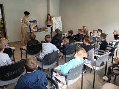 Na zdjęciu znajdują się uczestnicy pasowania. Dzieci siedzą na krzesłach. Zdjęcie wykonano w bibliotece.
