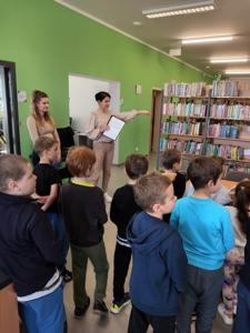Na zdjęciu znajdują się uczestnicy pasowania. Dzieci stoją. Zdjęcie wykonano w bibliotece.
