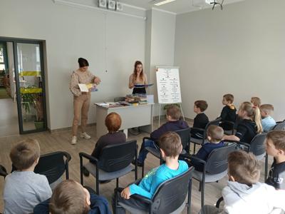 Na zdjęciu znajdują się uczestnicy pasowania. Dzieci siedzą na krzesłach. Zdjęcie wykonano w bibliotece.