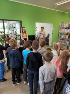Na zdjęciu znajdują się uczestnicy pasowania. Dzieci stoją. Zdjęcie wykonano w bibliotece.