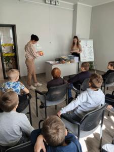 Na zdjęciu znajdują się uczestnicy pasowania. Dzieci siedzą na krzesłach. Zdjęcie wykonano w bibliotece.