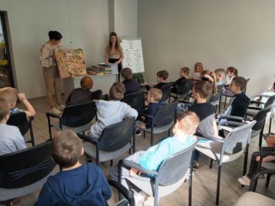 Na zdjęciu znajdują się uczestnicy pasowania. Dzieci siedzą na krzesłach. Zdjęcie wykonano w bibliotece.