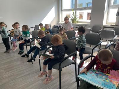 Na zdjęciu znajdują się uczestnicy pasowania. Dzieci siedzą na krzesłach. Zdjęcie wykonano w bibliotece.