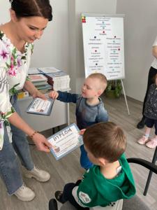 Na zdjęciu znajdują się uczestnicy pasowania. Dzieci siedzą na krzesłach. Zdjęcie wykonano w bibliotece.