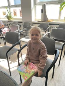 Na zdjęciu znajdują się uczestnicy pasowania. Dzieci siedzą na krzesłach. Zdjęcie wykonano w bibliotece.