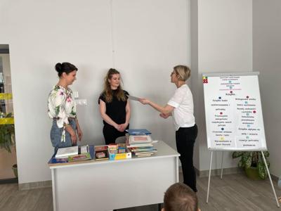 Na zdjęciu znajdują się uczestnicy pasowania. Dzieci siedzą na krzesłach. Zdjęcie wykonano w bibliotece.