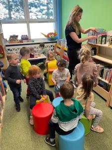 Na zdjęciu znajdują się uczestnicy pasowania. Dzieci znajdują się pomiędzy regałami z książkami. Zdjęcie wykonano w bibliotece.