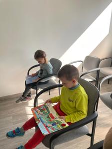 Na zdjęciu znajdują się uczestnicy pasowania. Dzieci siedzą na krzesłach. Zdjęcie wykonano w bibliotece.