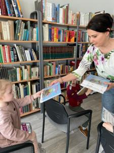 Na zdjęciu znajdują się uczestnicy pasowania. Dzieci siedzą na krzesłach. Zdjęcie wykonano w bibliotece.