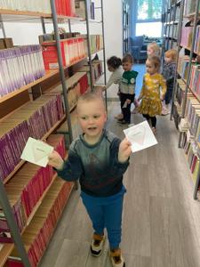 Na zdjęciu znajdują się uczestnicy pasowania. Dzieci znajdują się pomiędzy regałami z książkami. Zdjęcie wykonano w bibliotece.