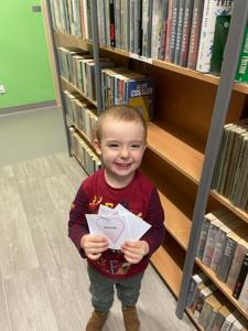Na zdjęciu znajdują się uczestnicy pasowania. Dzieci znajdują się pomiędzy regałami z książkami. Zdjęcie wykonano w bibliotece.