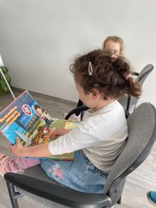 Na zdjęciu znajdują się uczestnicy pasowania. Dzieci siedzą na krzesłach. Zdjęcie wykonano w bibliotece.