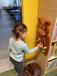 Na zdjęciu znajdują się uczestnicy pasowania. Dzieci znajdują się pomiędzy regałami z książkami. Zdjęcie wykonano w bibliotece.