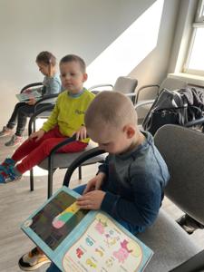 Na zdjęciu znajdują się uczestnicy pasowania. Dzieci siedzą na krzesłach. Zdjęcie wykonano w bibliotece.