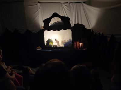 Na zdjęciu znajdują się uczestnicy przedstawienia. Dzieci i rodzice siedzą na krzesłach i poduszkach. W tle scenka teatralna.