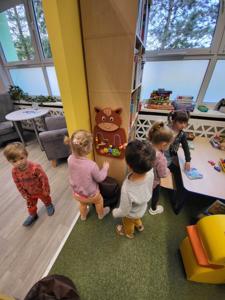 Na zdjęciu znajdują się uczestnicy warsztatów. Dzieci oglądają książki. Zdjęcie wykonano w bibliotece.