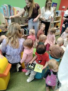 Na zdjęciu znajdują się uczestnicy warsztatów. Dzieci oglądają książki. Zdjęcie wykonano w bibliotece.