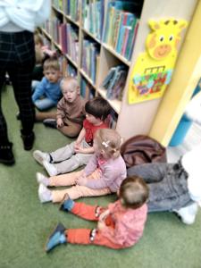 Na zdjęciu znajdują się uczestnicy warsztatów. Dzieci siedzą pomiędzy regałami. Zdjęcie wykonano w bibliotece.