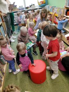 Na zdjęciu znajdują się uczestnicy warsztatów. Dzieci oglądają książki. Zdjęcie wykonano w bibliotece.