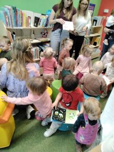 Na zdjęciu znajdują się uczestnicy warsztatów. Dzieci oglądają książki. Zdjęcie wykonano w bibliotece.