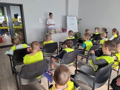 Na zdjęciu znajdują się uczestnicy zajęć. Dzieci siedzą na krzesłach. Zdjęcie wykonano w bibliotece.