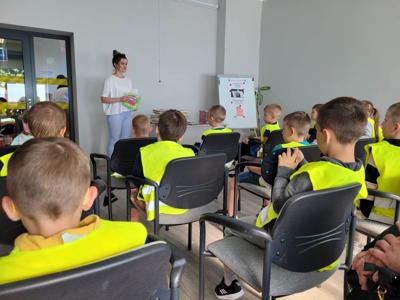 Na zdjęciu znajdują się uczestnicy zajęć. Dzieci siedzą na krzesłach. Zdjęcie wykonano w bibliotece.