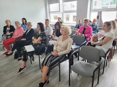 Na zdjęciu znajdują się uczestnicy warsztatów. Uczestnicy siedzą na krzesłach.