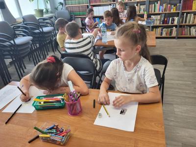 Na zdjęciu znajdują się uczestnicy zajęć. Dzieci wykonują prace plastyczne i powierzone im zadania.