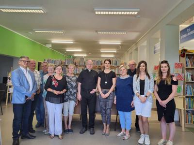Na zdjęciu znajdują się uczestnicy spotkania autorskiego. W tle księgozbiór biblioteki. Zdjęcie wykonano w bibliotece.