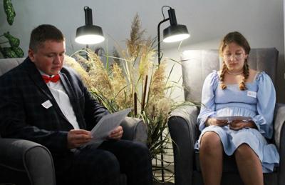 Na zdjęciu znajdują się uczestnicy czytający książkę siedząc na fotelach. Zdjęcie wykonano w bibliotece.