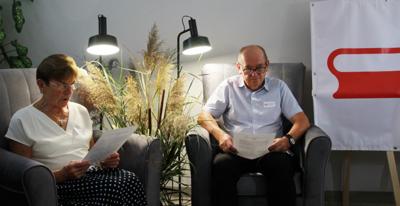 Na zdjęciu znajdują się uczestnicy czytający książkę siedząc na fotelach. Zdjęcie wykonano w bibliotece.
