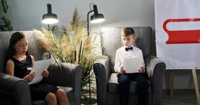 Na zdjęciu znajdują się uczestnicy czytający książkę siedząc na fotelach. Zdjęcie wykonano w bibliotece.