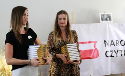 Na zdjęciu znajdują się pracownicy biblioteki. Bibliotekarki trzymają w ręce książki. Zdjęcie wykonano w bibliotece.