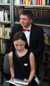 Na zdjęciu znajdują uczestnicy ,,Narodowego Czytania''. W tle księgozbiór biblioteki.