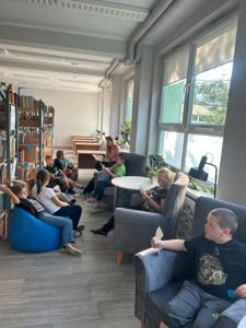 Na zdjęciu znajdują się uczestnicy zajęć. Dzieci siedzą na pufach. Zdjęcie wykonano w bibliotece.