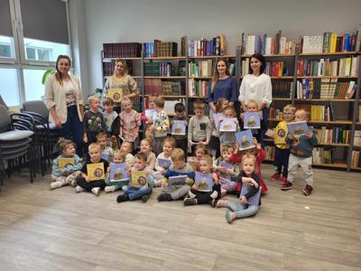 Na zdjęciu znajdują się uczestnicy zajęć. W tle księgozbiór biblioteki. Zdjęcie wykonano w bibliotece.