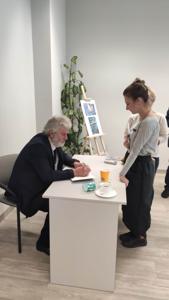 Na zdjęciu znajduje się autor Zbigniew Kołba trzymający książkę. W tle uczestnicy spotkania.