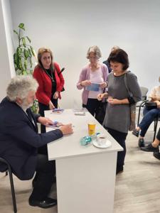 Na zdjęciu znajduje się autor Zbigniew Kołba trzymający książkę. W tle uczestnicy spotkania.