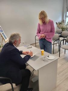 Na zdjęciu znajduje się autor Zbigniew Kołba trzymający książkę. W tle uczestnicy spotkania.