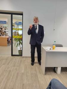 Na zdjęciu znajduje się prelegent. Zdjęcie wykonano w bibliotece.