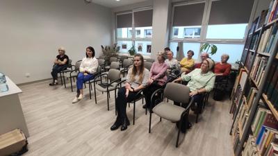 Na zdjęciu znajdują się uczestnicy spotkania autorskiego. Uczestnicy siedzą na krzesłach.