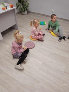 Na zdjęciu znajdują się uczestnicy warsztatów. Dzieci siedzą na podłodze.
