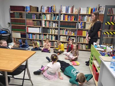 Na zdjęciu znajdują się uczestnicy zajęć. Dzieci siedzą na podłodze.