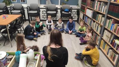 Na zdjęciu znajdują się uczestnicy zajęć. Dzieci siedzą na podłodze.