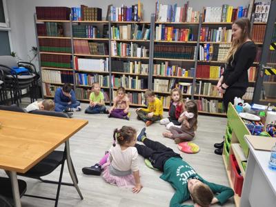Na zdjęciu znajdują się uczestnicy zajęć. Dzieci siedzą na podłodze.