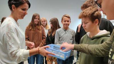 Na zdjęciu znajdują się uczestnicy wykładu. Młodzież otrzymuje przypinki.