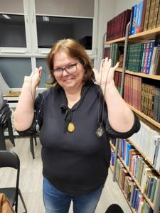Na zdjęciu znajduje się uczestniczka warsztatów. Uczestniczka trzyma w rękach biżuterię.